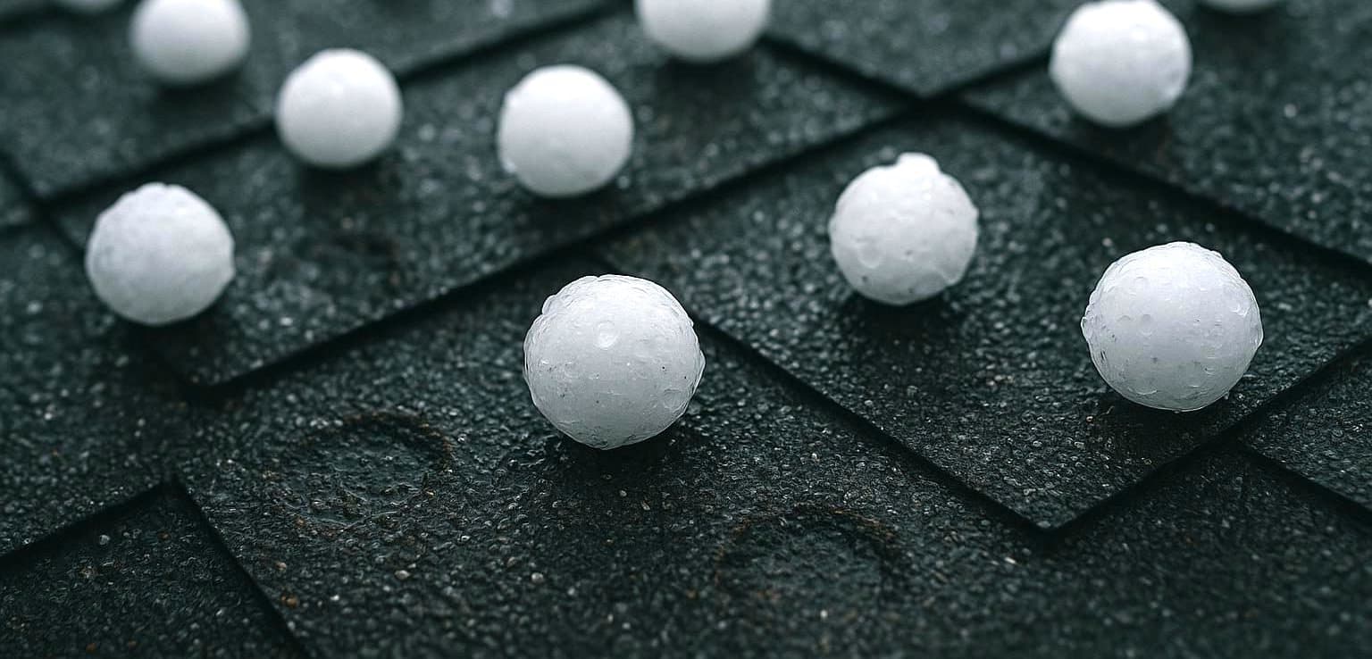 Hailstones on asphalt roof shingles after a Texas storm